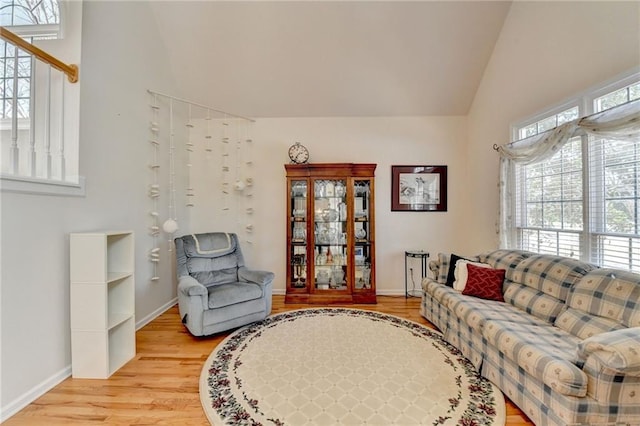 living room with lofted ceiling, baseboards, and light wood finished floors