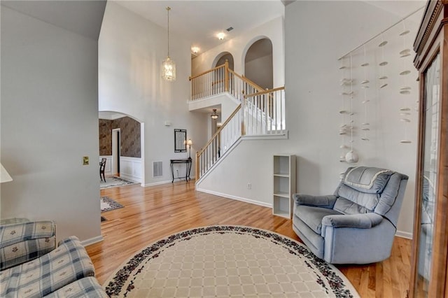 living area with visible vents, baseboards, stairs, wood finished floors, and arched walkways