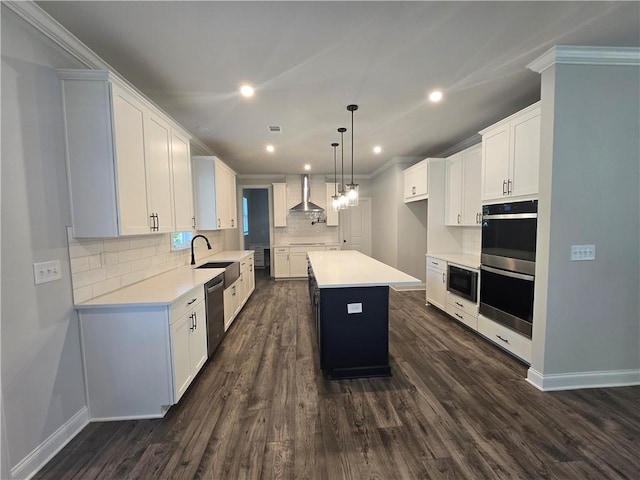 kitchen with stainless steel appliances, wall chimney range hood, a kitchen island, decorative backsplash, and white cabinets