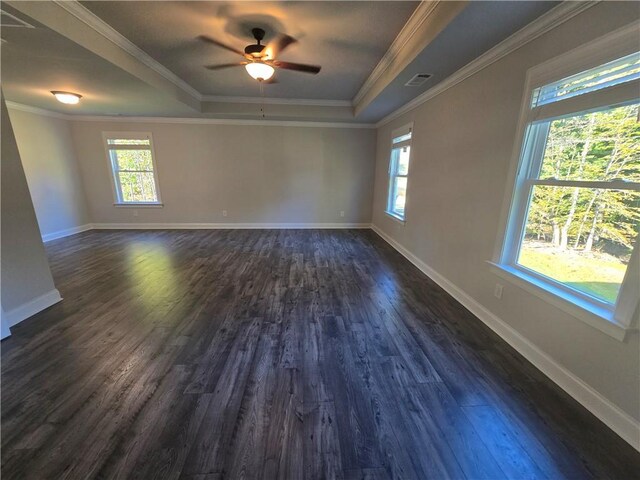 spare room with a tray ceiling, crown molding, ceiling fan, and dark wood-type flooring