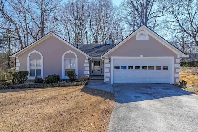 ranch-style home featuring an attached garage, a chimney, concrete driveway, and stucco siding