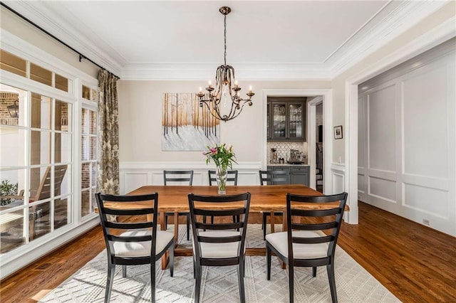 dining space featuring hardwood / wood-style floors, crown molding, and a notable chandelier