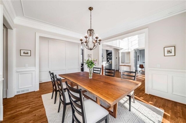 dining space featuring crown molding, hardwood / wood-style floors, and a chandelier