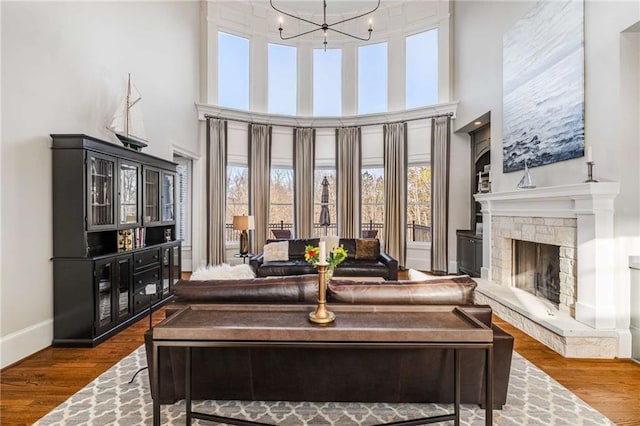 living room featuring hardwood / wood-style flooring, a fireplace, a high ceiling, and an inviting chandelier