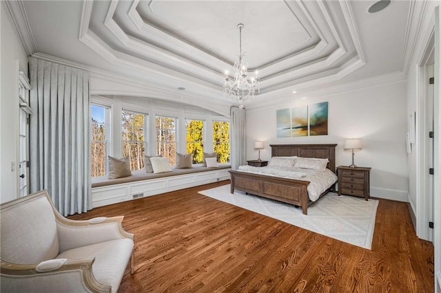 bedroom with a notable chandelier, a raised ceiling, light wood-type flooring, and ornamental molding