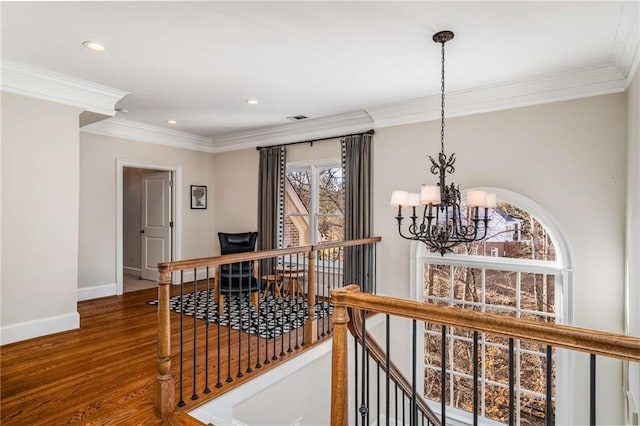 corridor with wood-type flooring, an inviting chandelier, a wealth of natural light, and ornamental molding