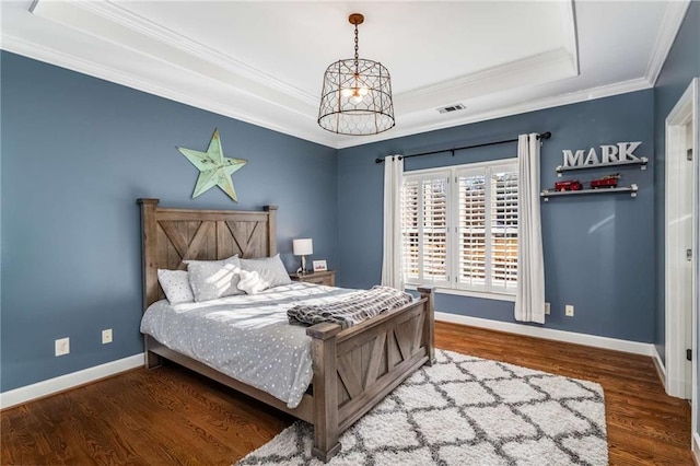 bedroom featuring ornamental molding, a raised ceiling, and dark wood-type flooring