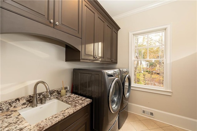 laundry room with cabinets, crown molding, sink, light tile patterned floors, and washing machine and dryer