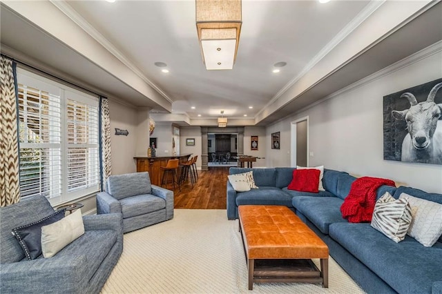 living room with a raised ceiling, crown molding, and wood-type flooring