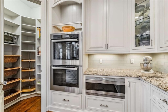 kitchen featuring light stone counters, white cabinets, and stainless steel double oven