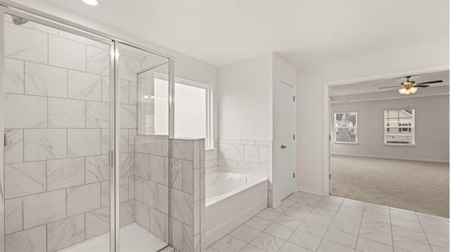 13567 Whitman Ln, Covington, GA 30014 - bathroom with a garden tub, a stall shower, a ceiling fan, marble look tiles, and baseboards