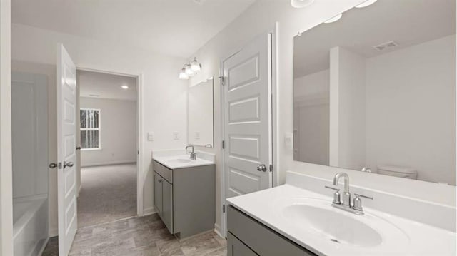 13567 Whitman Ln, Covington, GA 30014 - bathroom featuring two vanities, toilet, and a tub to relax in