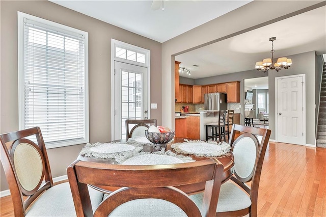 dining area with light wood-style floors, baseboards, stairs, and a chandelier