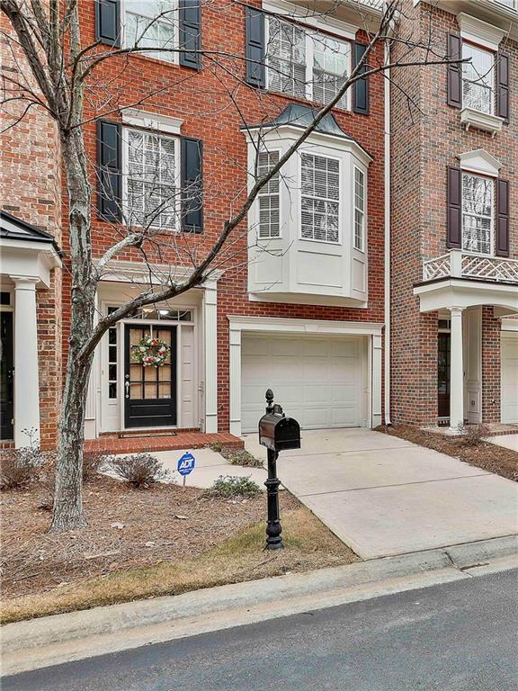 townhome / multi-family property featuring driveway, brick siding, and an attached garage