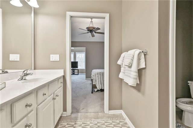 ensuite bathroom featuring toilet, a ceiling fan, vanity, ensuite bath, and baseboards