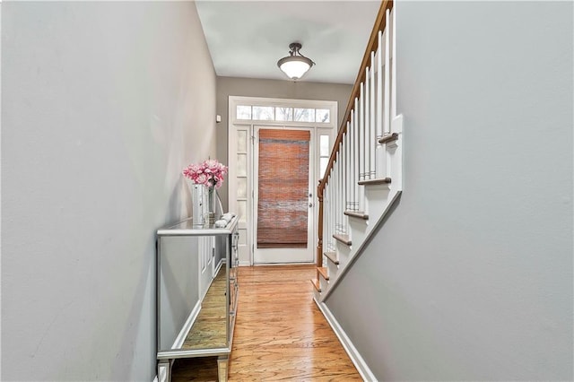 doorway to outside featuring light wood-type flooring, stairway, and baseboards