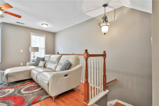 living area with light wood-type flooring, ceiling fan, visible vents, and vaulted ceiling