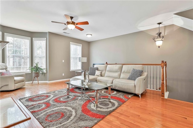 living area featuring ceiling fan, hardwood / wood-style floors, visible vents, and baseboards