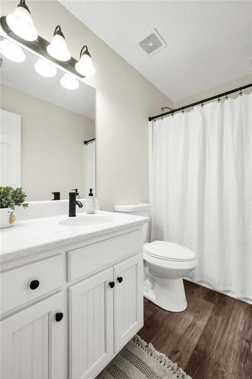 254 Barnesville Rd, Milner, GA 30257 - full bath with wood finished floors, visible vents, toilet, vanity, and a textured ceiling