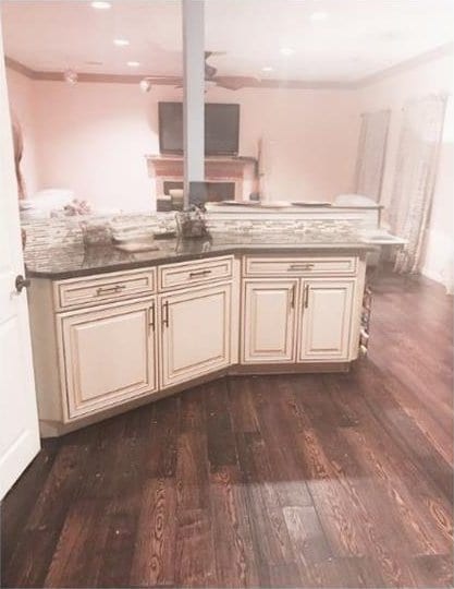 kitchen featuring cream cabinetry, crown molding, ceiling fan, and dark wood-type flooring