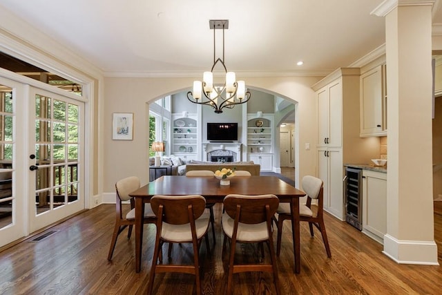 4310 Granby Way, Marietta, GA 30062 - dining space featuring wine cooler, arched walkways, ornamental molding, a fireplace, and dark wood-style floors