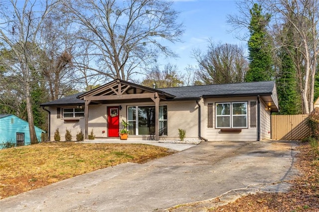 single story home featuring brick siding, driveway, and fence