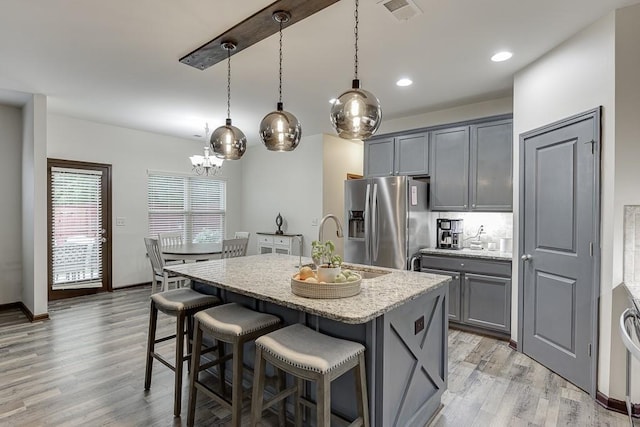 893 Whitfield Oak Rd, Auburn, GA 30011 - kitchen featuring stainless steel refrigerator with ice dispenser, gray cabinets, a kitchen bar, light wood-style flooring, and light stone counters