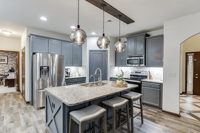 893 Whitfield Oak Rd, Auburn, GA 30011 - kitchen with appliances with stainless steel finishes, a sink, arched walkways, light stone counters, and a breakfast bar