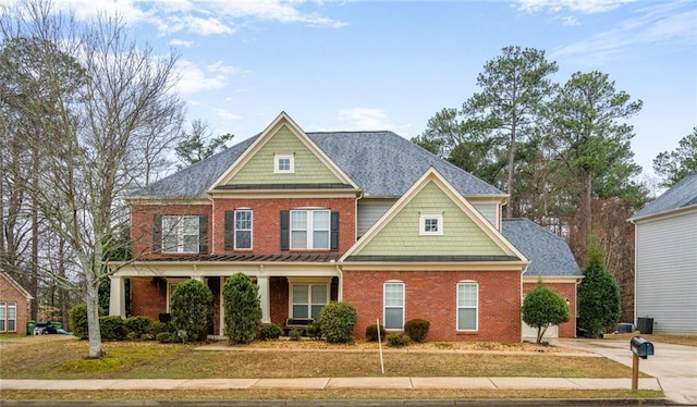 craftsman inspired home featuring a standing seam roof, a shingled roof, a front yard, and brick siding