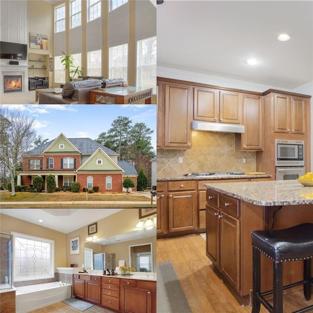 kitchen with light wood finished floors, a kitchen breakfast bar, under cabinet range hood, appliances with stainless steel finishes, and open floor plan