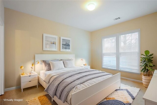 bedroom with baseboards, visible vents, and light colored carpet