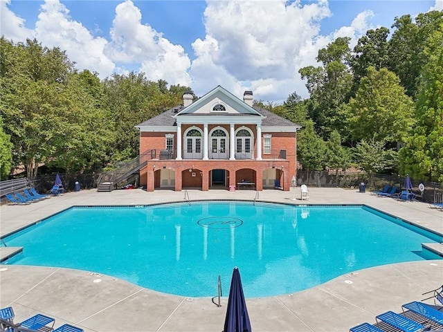 community pool featuring fence, a patio area, and stairs