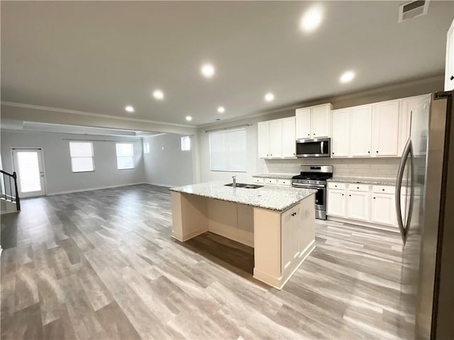 kitchen featuring tasteful backsplash, visible vents, appliances with stainless steel finishes, open floor plan, and a sink