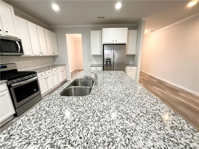 kitchen featuring visible vents, backsplash, appliances with stainless steel finishes, white cabinets, and a sink