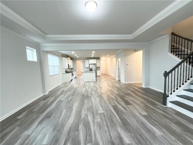 unfurnished living room featuring stairway, baseboards, ornamental molding, and wood finished floors