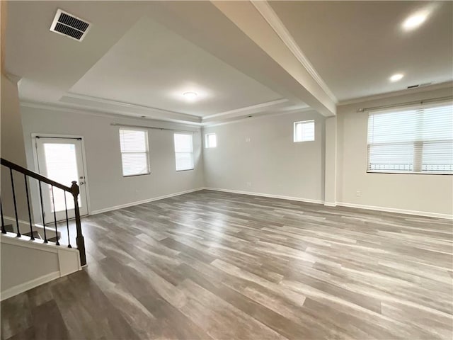 interior space with a tray ceiling, crown molding, visible vents, stairway, and wood finished floors