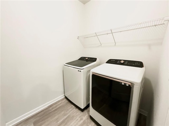 laundry area featuring laundry area, baseboards, separate washer and dryer, and light wood-style floors