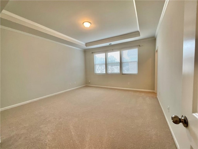 spare room with baseboards, a tray ceiling, crown molding, and light colored carpet