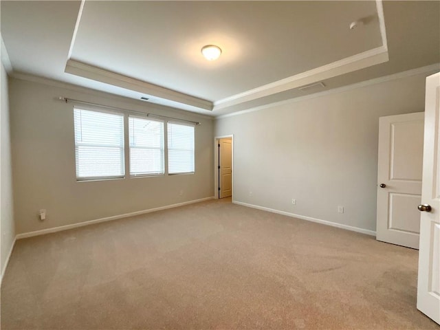 unfurnished room with crown molding, a tray ceiling, light carpet, and baseboards