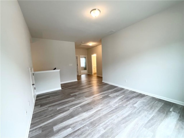 empty room featuring attic access, visible vents, baseboards, and wood finished floors