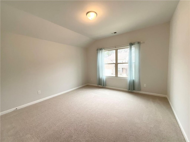 unfurnished room with baseboards, visible vents, vaulted ceiling, and light colored carpet