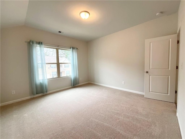 carpeted spare room featuring lofted ceiling, visible vents, and baseboards