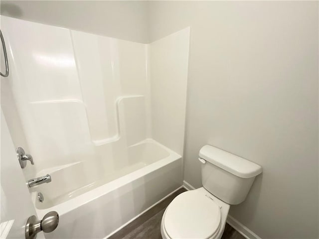 bathroom with bathtub / shower combination, baseboards, and toilet