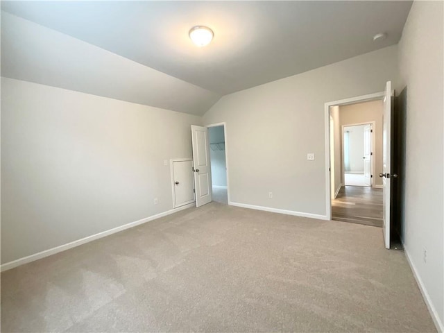 unfurnished bedroom featuring lofted ceiling, carpet flooring, and baseboards