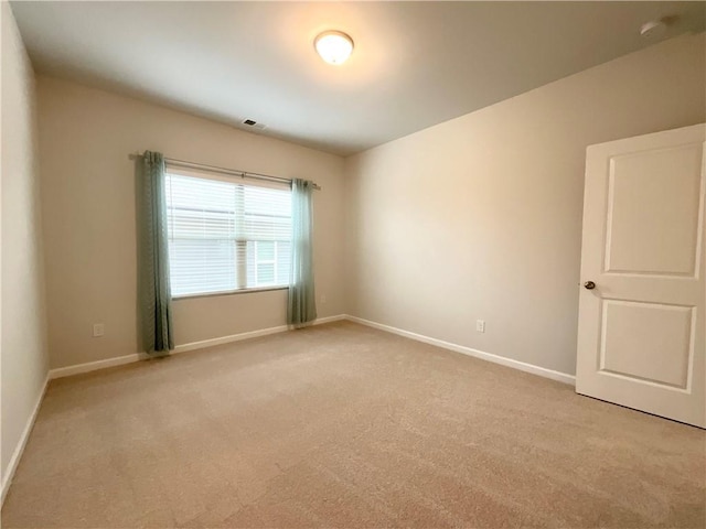 spare room featuring visible vents, light colored carpet, and baseboards