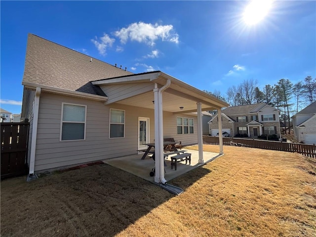 rear view of property featuring a yard, roof with shingles, fence, and a patio