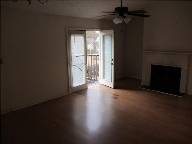 unfurnished living room with a textured ceiling, ceiling fan, a fireplace, and wood finished floors