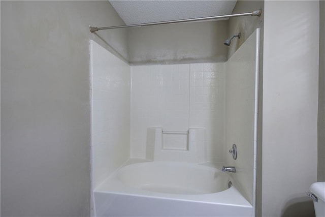 bathroom with a textured ceiling, bathtub / shower combination, and toilet