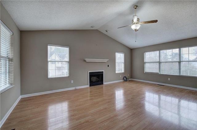 unfurnished living room featuring lofted ceiling, light hardwood / wood-style flooring, and a textured ceiling