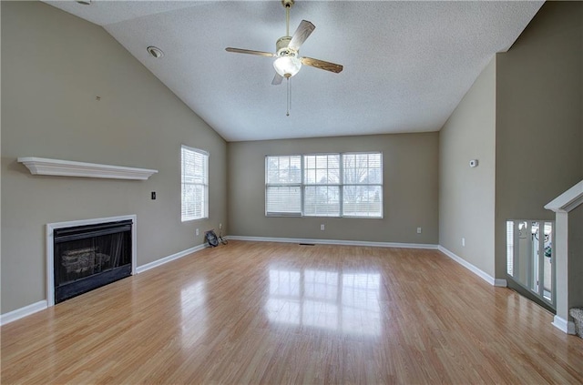 unfurnished living room featuring ceiling fan, lofted ceiling, a textured ceiling, and light hardwood / wood-style flooring